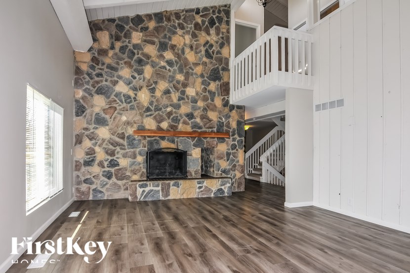 A stone fireplace in a room with wooden floors and white walls.