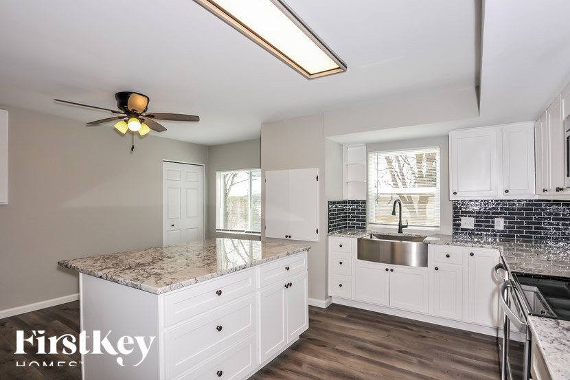 A kitchen with a marble countertop and white cabinets.