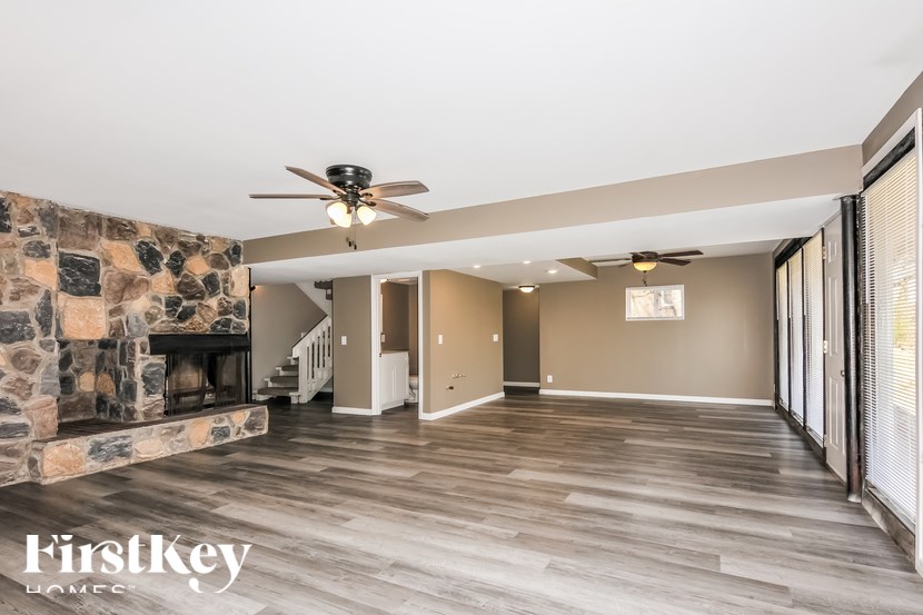 A spacious living room with a stone fireplace and wood flooring.