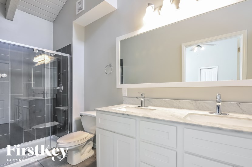 A white bathroom with a glass shower stall and a toilet.