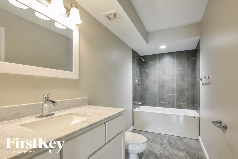 A modern bathroom with a marble sink and a walk-in shower.