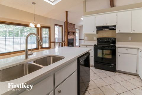 A kitchen with a stainless steel sink and black and white appliances.