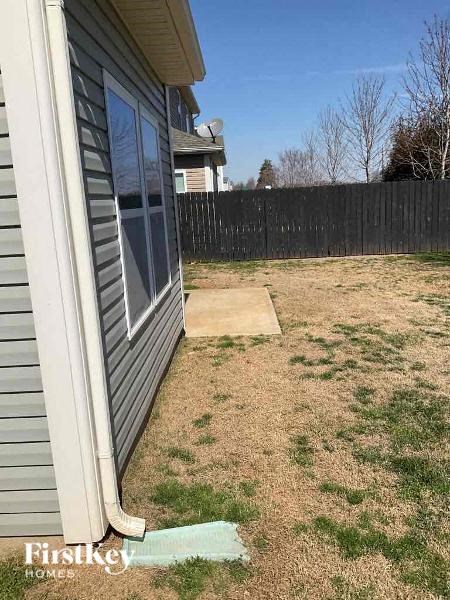 A backyard with a wooden fence and a small patch of grass.