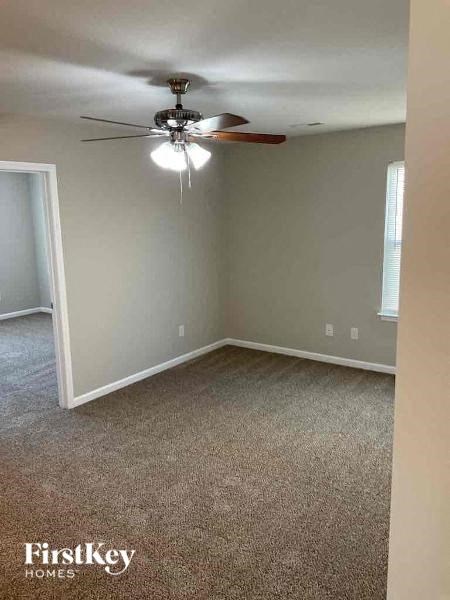 A room with a ceiling fan and carpeted floor.