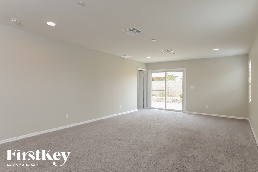 A spacious room with a carpeted floor and a sliding glass door leading to a balcony.