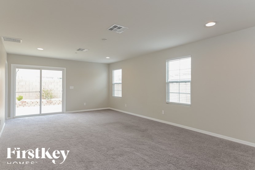 A spacious room with a carpeted floor and two windows.