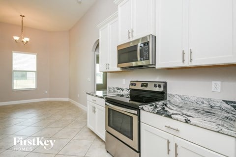 a kitchen with white cabinets and a stove and a microwave