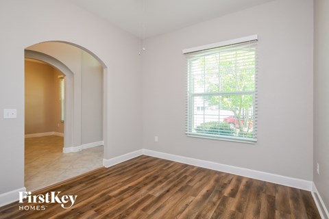 the living room and dining room of a home with wood flooring and a window