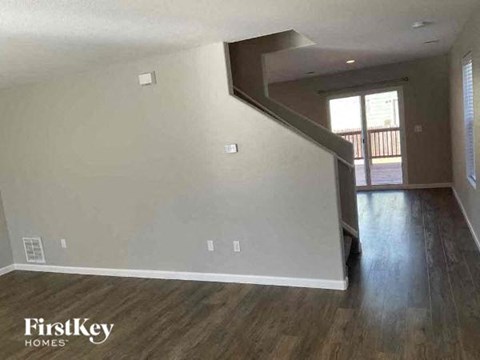 an empty living room with wood floors and a staircase