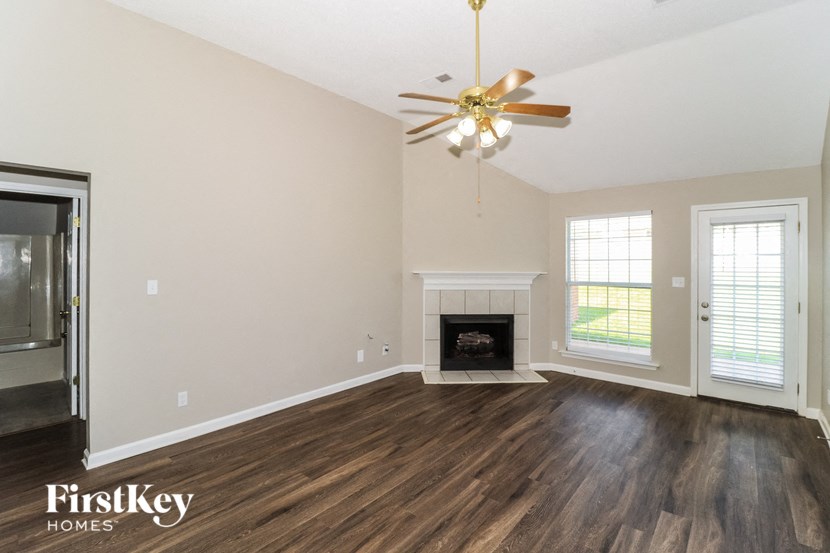 an empty living room with a ceiling fan and a fireplace