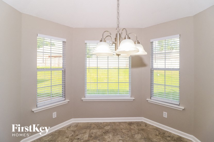 an empty dining room with three windows and a chandelier