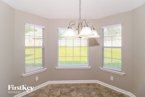 an empty dining room with three windows and a chandelier