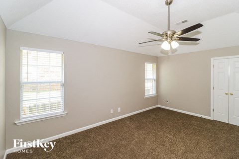 an empty bedroom with a ceiling fan and window