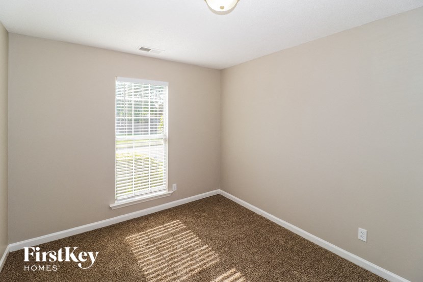 an empty room with a window and a brown carpet