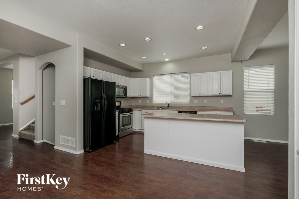 a kitchen with white cabinets and a black refrigerator