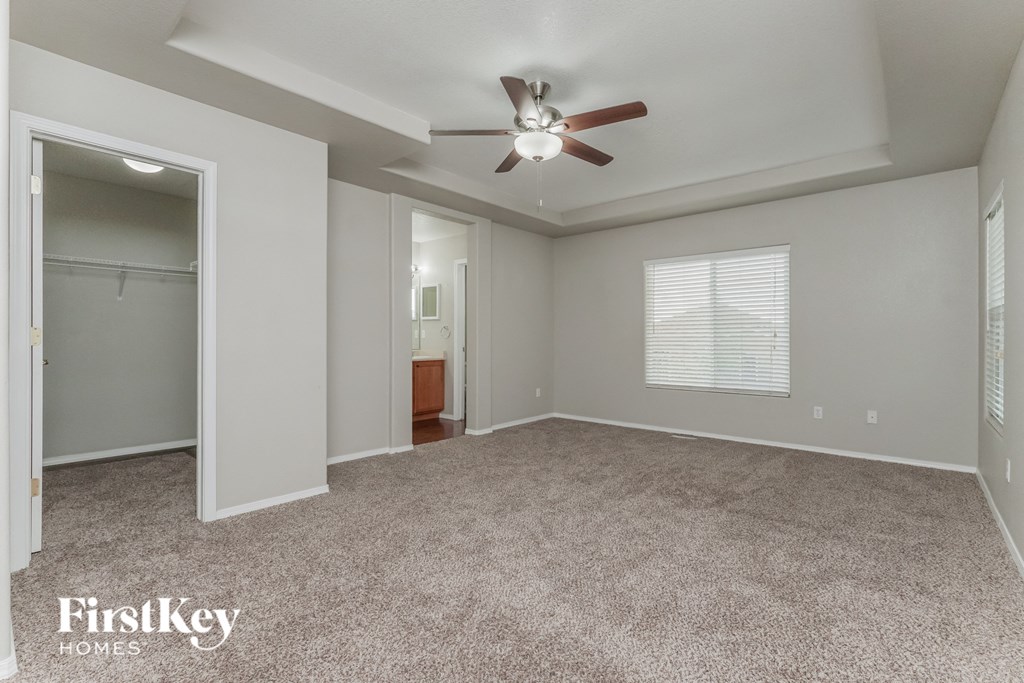 an empty living room with a ceiling fan and a closet