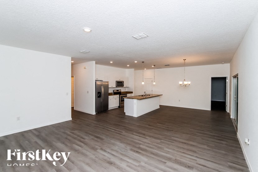 A spacious kitchen with a wooden floor and white walls.