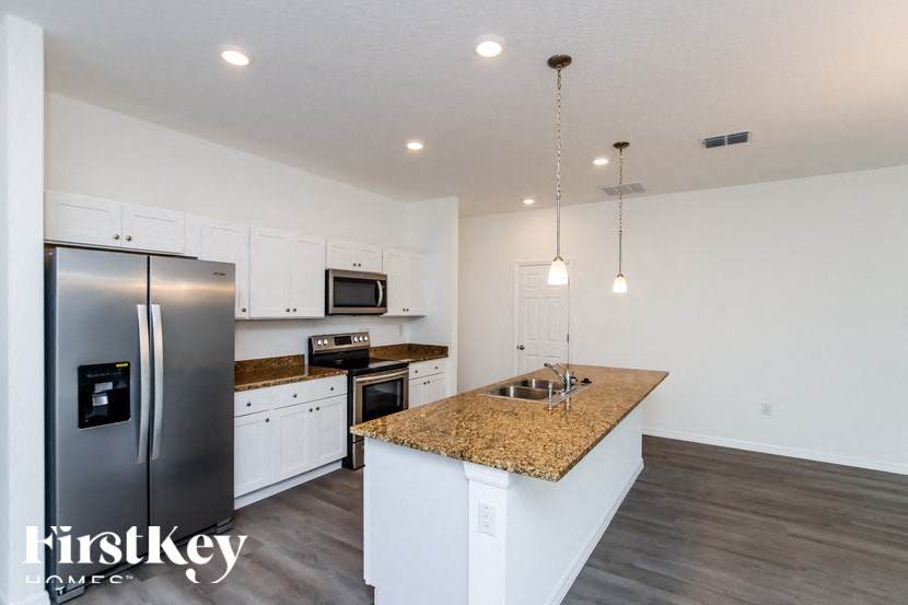 A kitchen with a granite countertop and a refrigerator with a digital display.