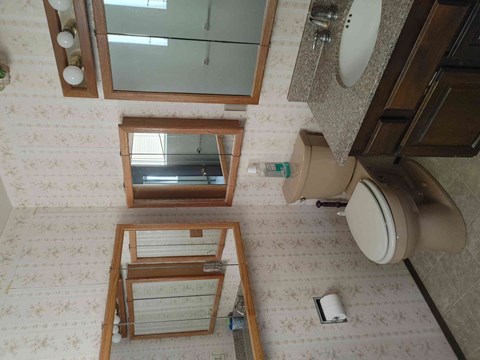 A bathroom with a toilet, sink, and mirror.