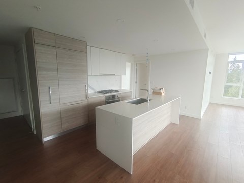 an empty kitchen with white cabinets and a wooden floor