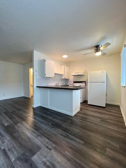 A kitchen with a white counter and a white fridge.