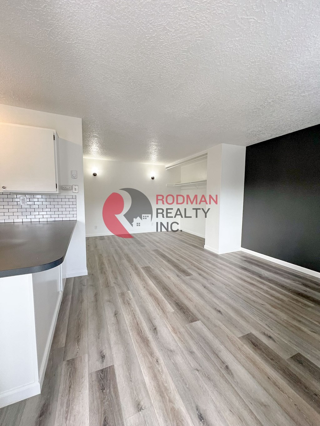A room with a wooden floor and a sign that says Rodman Realty Inc.