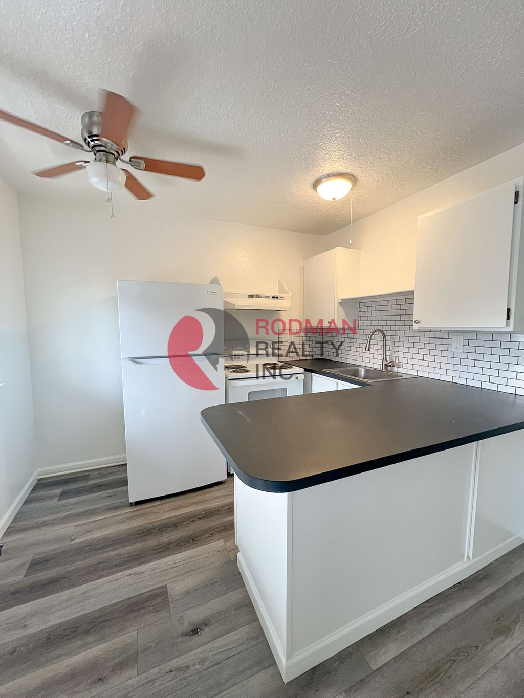 A kitchen with white cabinets and a black countertop.