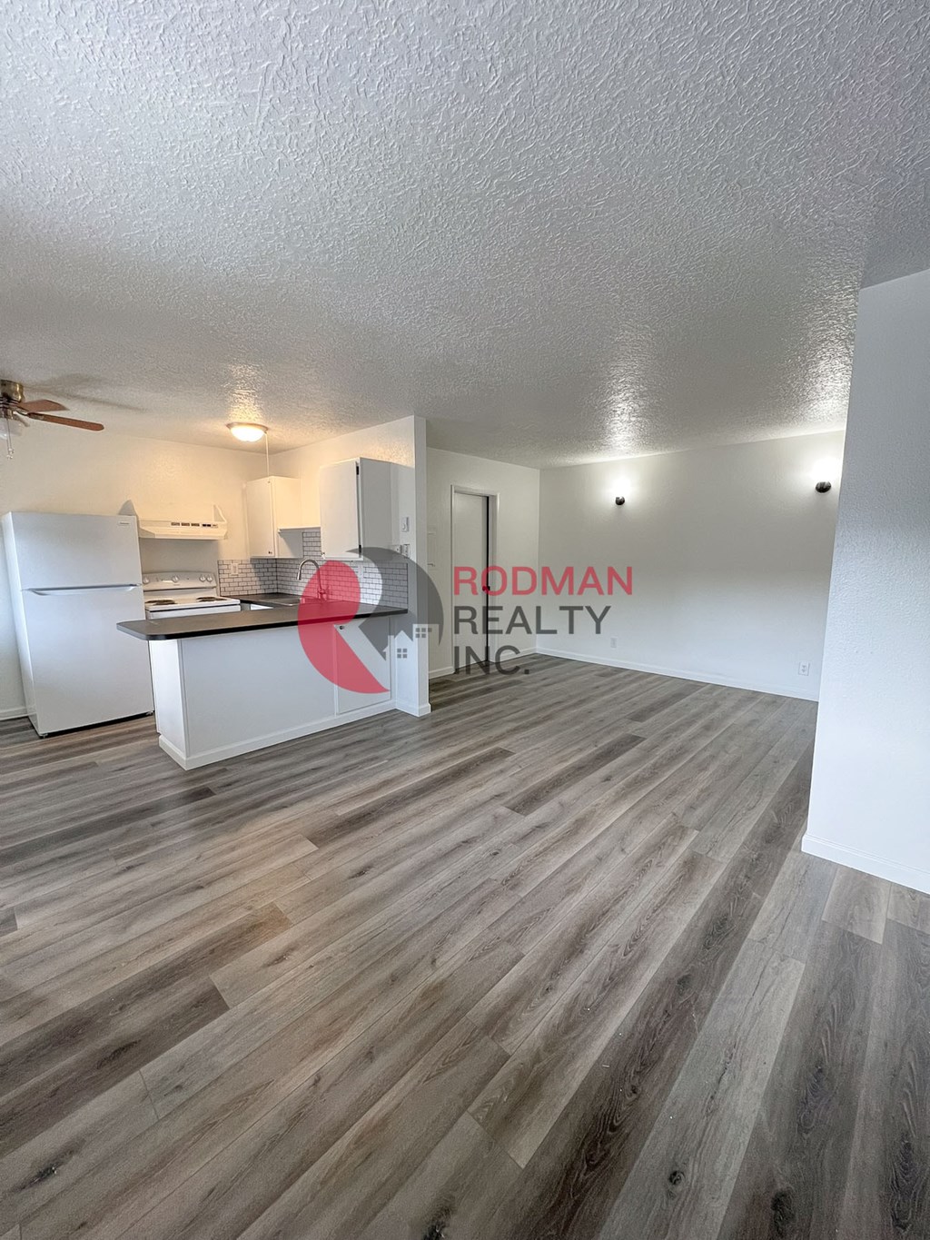 A room with a wooden floor and a white ceiling with a fan.