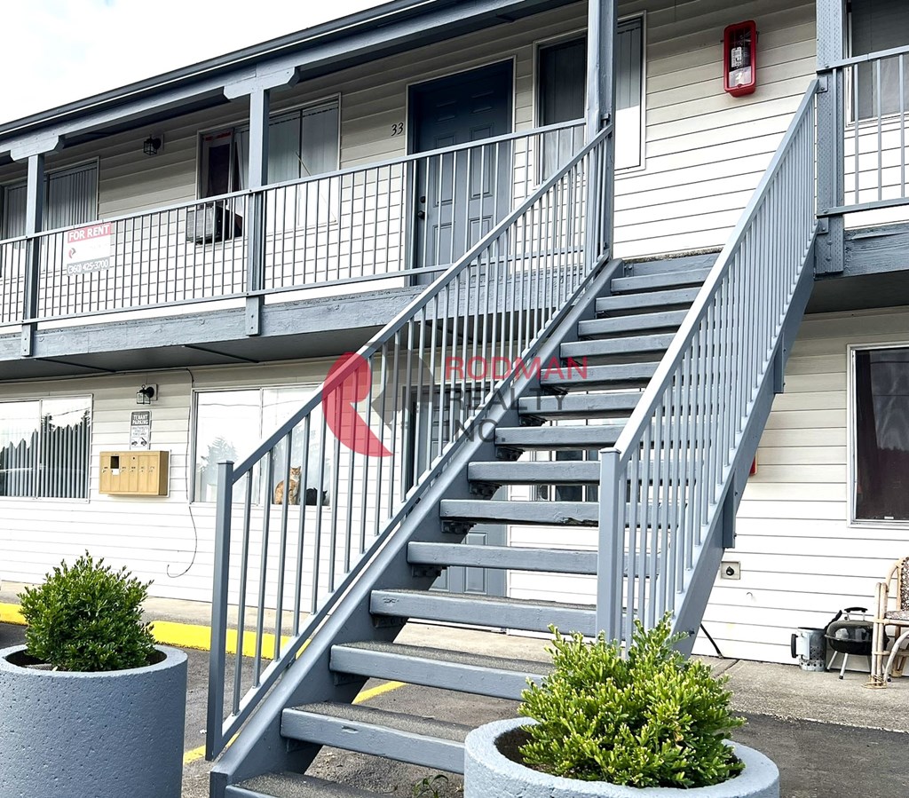 A staircase with a metal railing leads up to a balcony on the second floor of a building.
