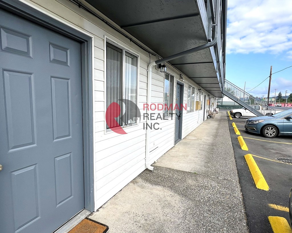 A blue door is on the left of a white building with a sign that says Rodman Realty Inc.