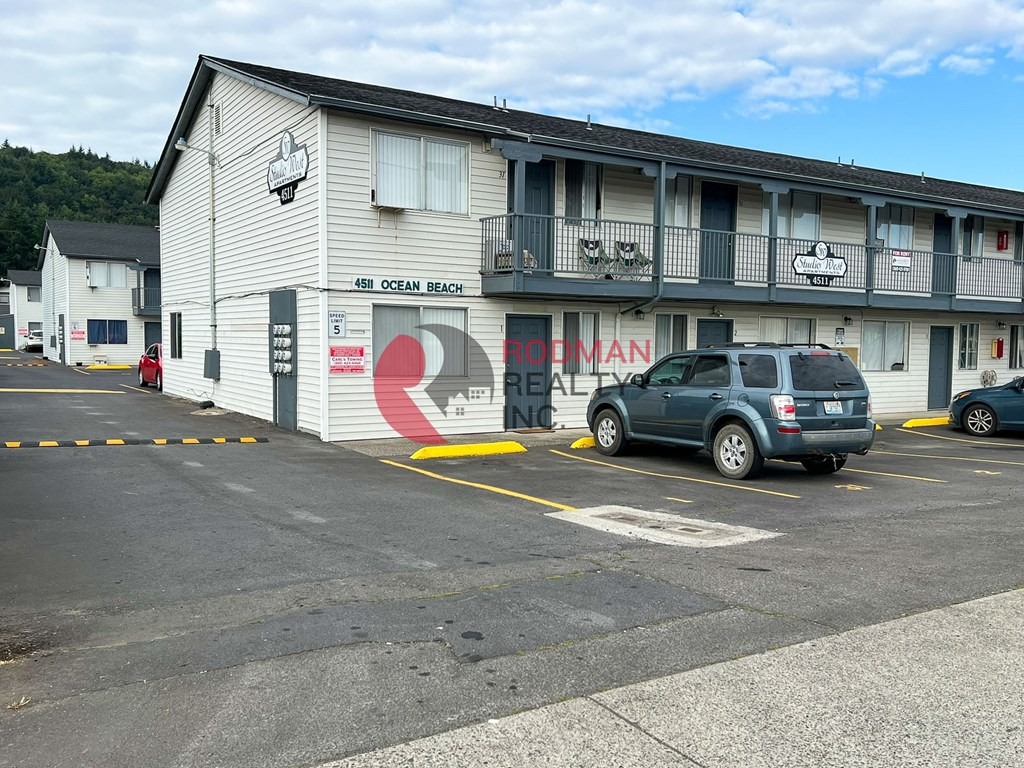 A parking lot in front of a motel with a car parked.