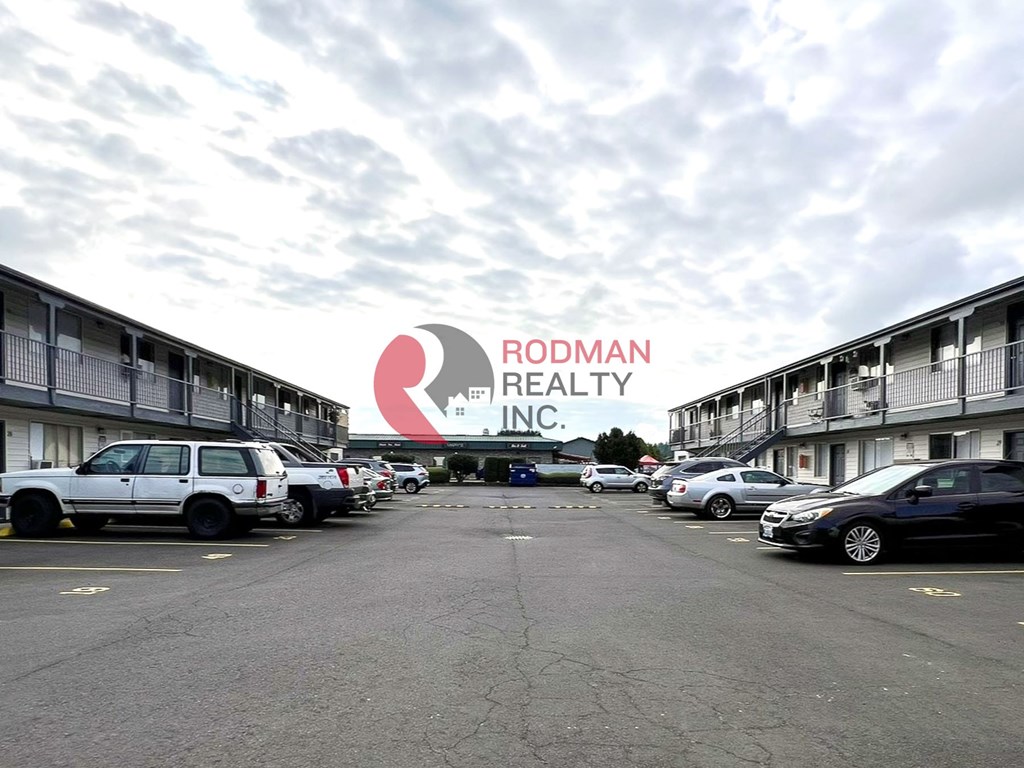 Rodman Realty Inc. logo in front of a parking lot with cars parked.