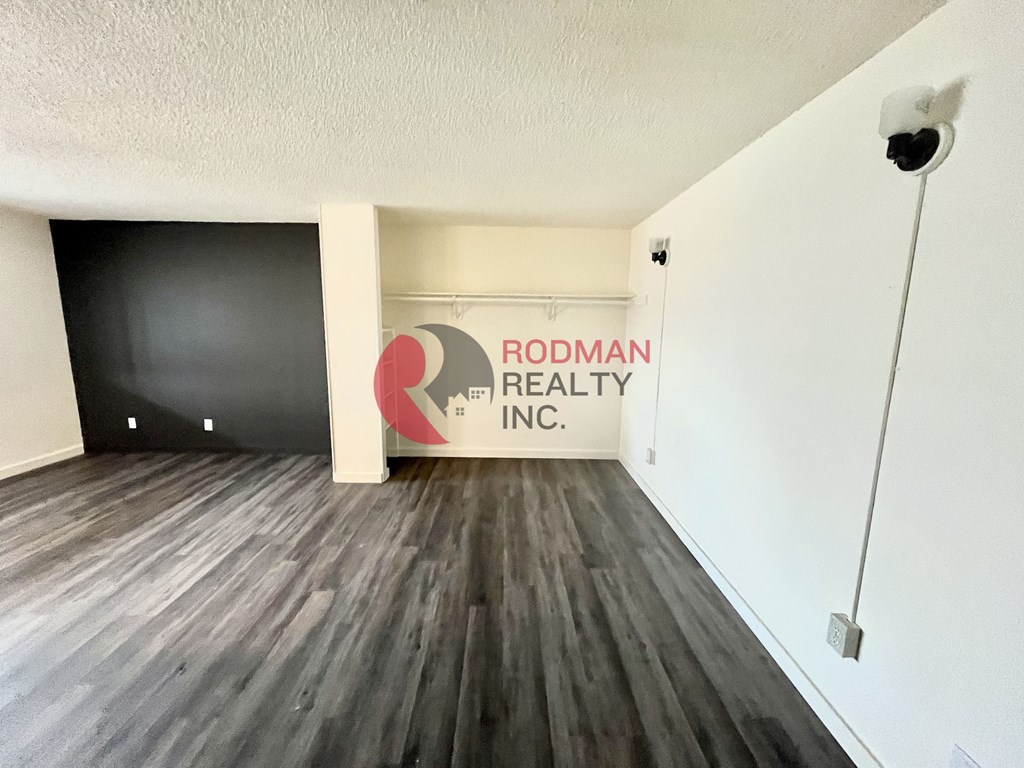A room with wooden flooring and a sign that says "Rodman Realty Inc.".