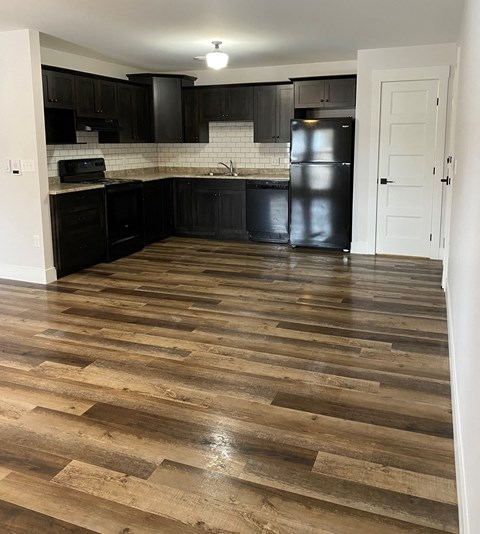 a kitchen with a wooden floor and black cabinets