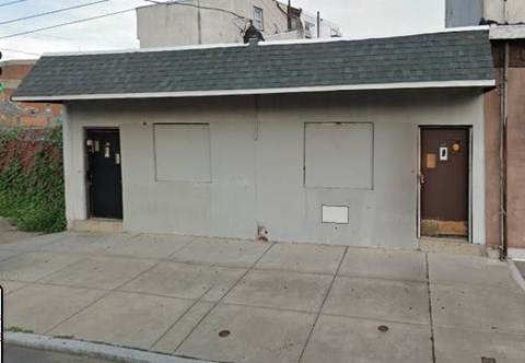 A small building with a grey roof and a brown door.