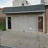 a small building with two doors on a sidewalk