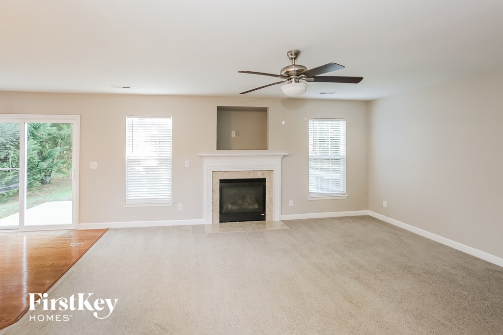 A spacious living room with a fireplace and a ceiling fan.