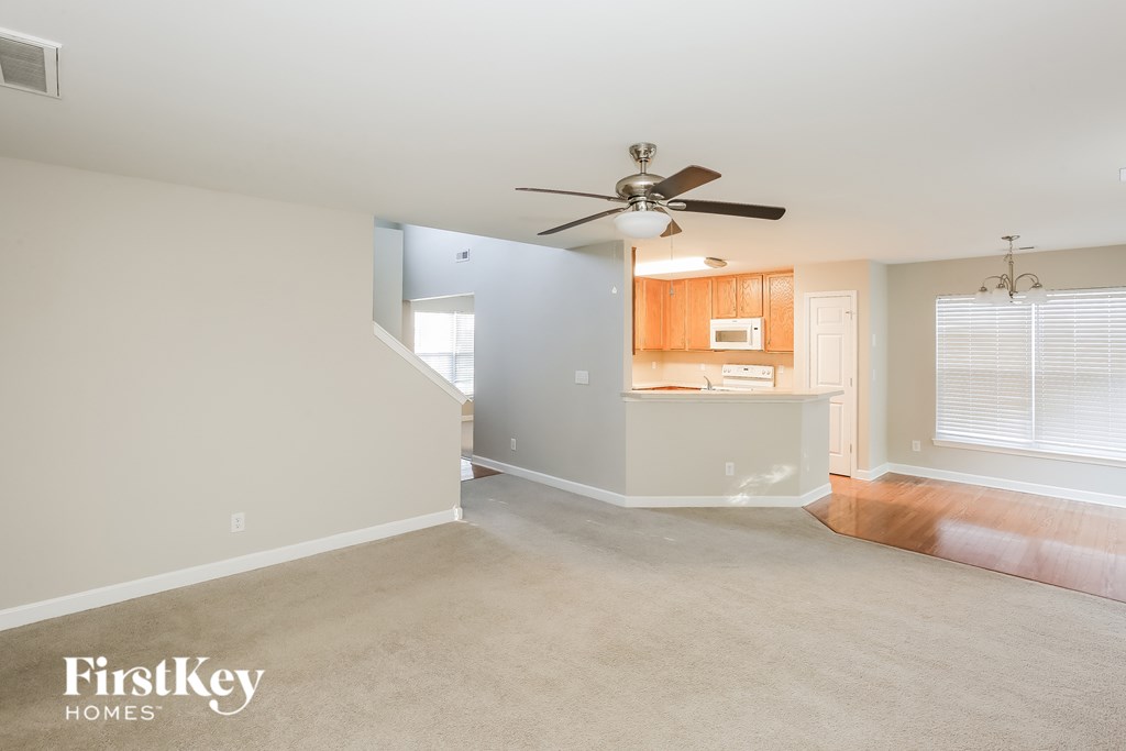 A spacious room with a ceiling fan and a staircase leading to another level.