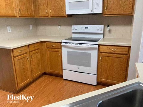 A kitchen with wooden cabinets and a white stove top oven.