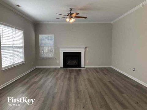 an empty living room with a ceiling fan and a fireplace
