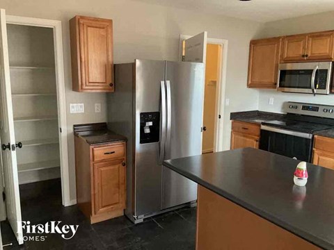 A kitchen with a refrigerator, oven, and microwave.