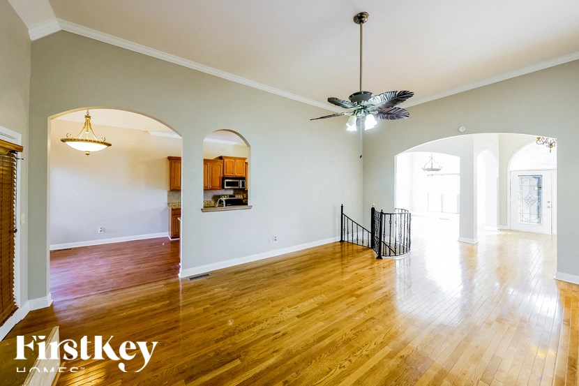 A spacious room with wooden floors and a ceiling fan.