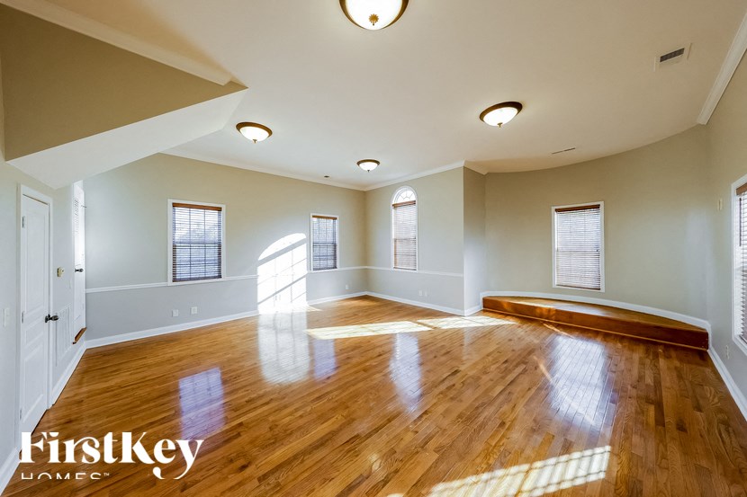 A spacious room with wooden floors and white walls.