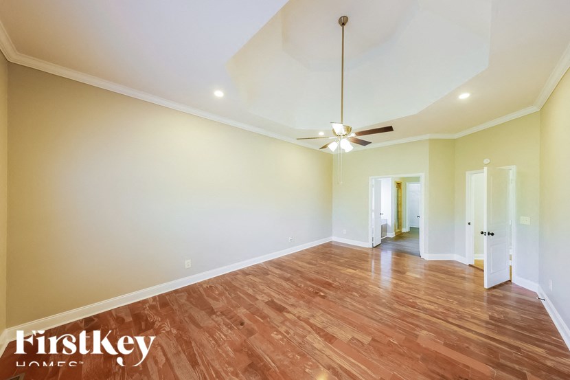 A spacious room with wooden floors and a ceiling fan.