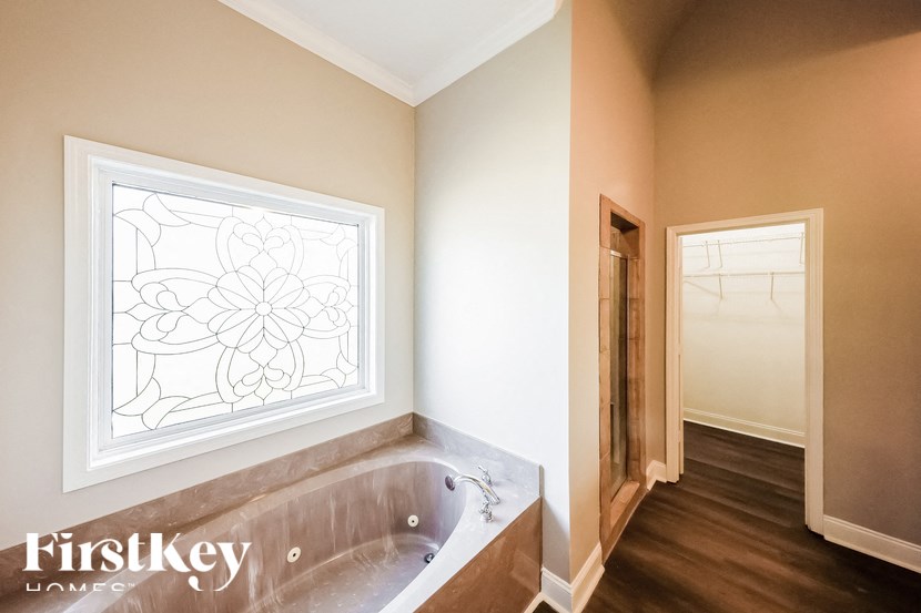 A bathroom with a tub and a window with a stained glass design.