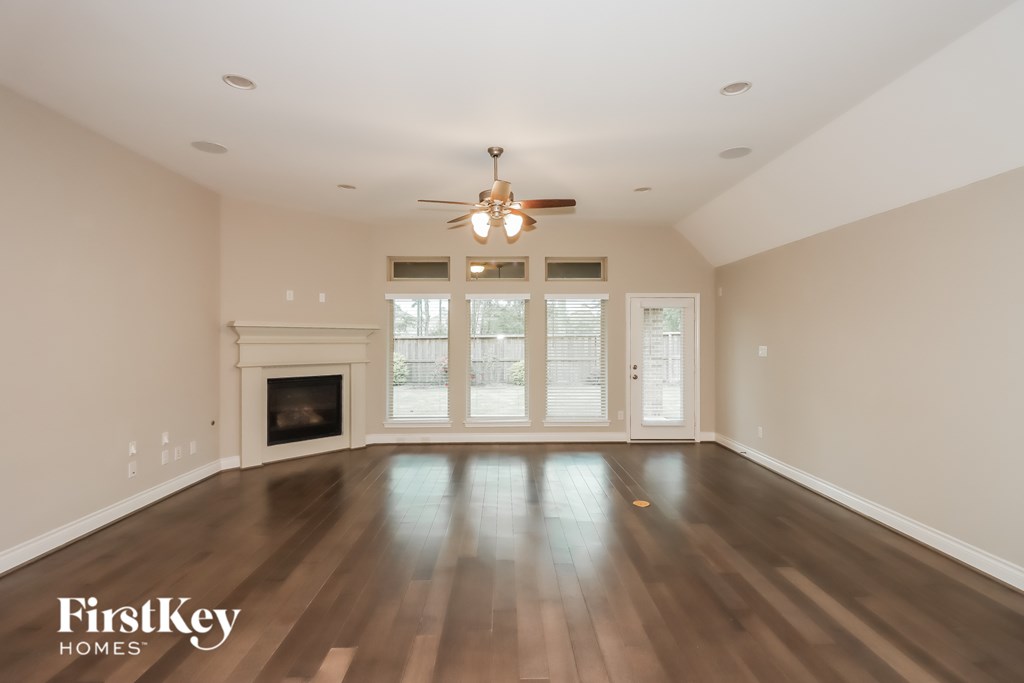 A spacious room with a fireplace and a ceiling fan.