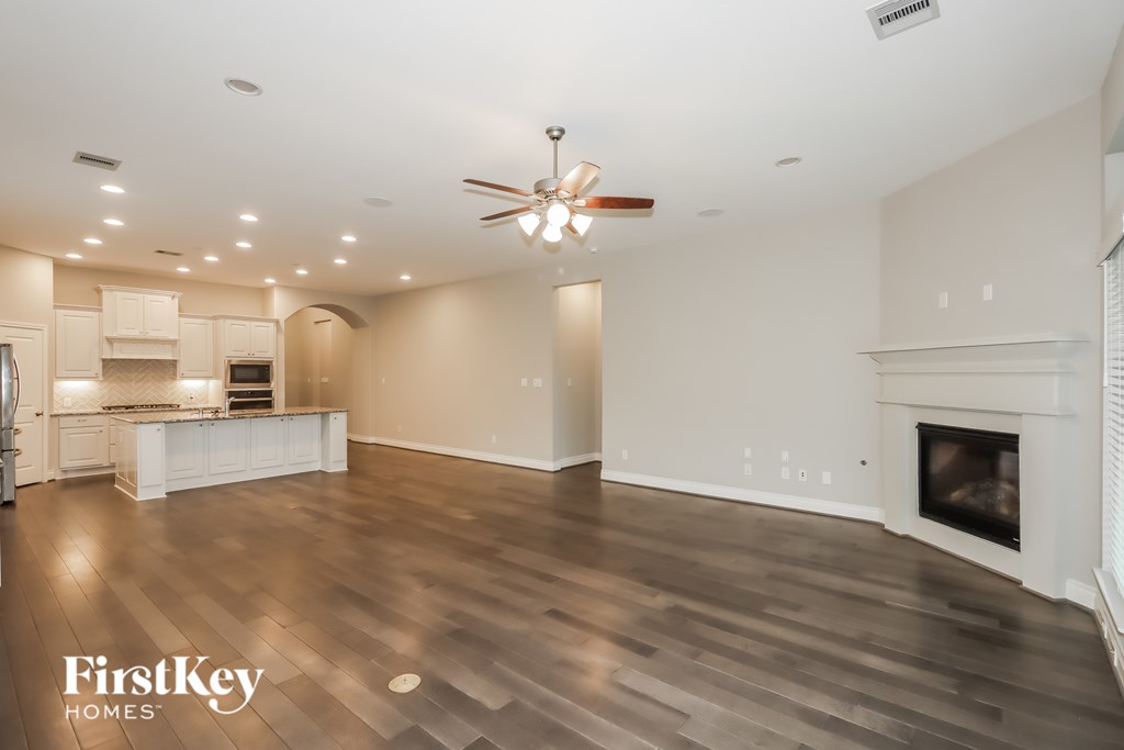 A spacious living room with a fireplace and a ceiling fan.