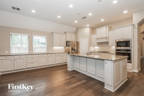 A spacious kitchen with white cabinets and a wooden floor.