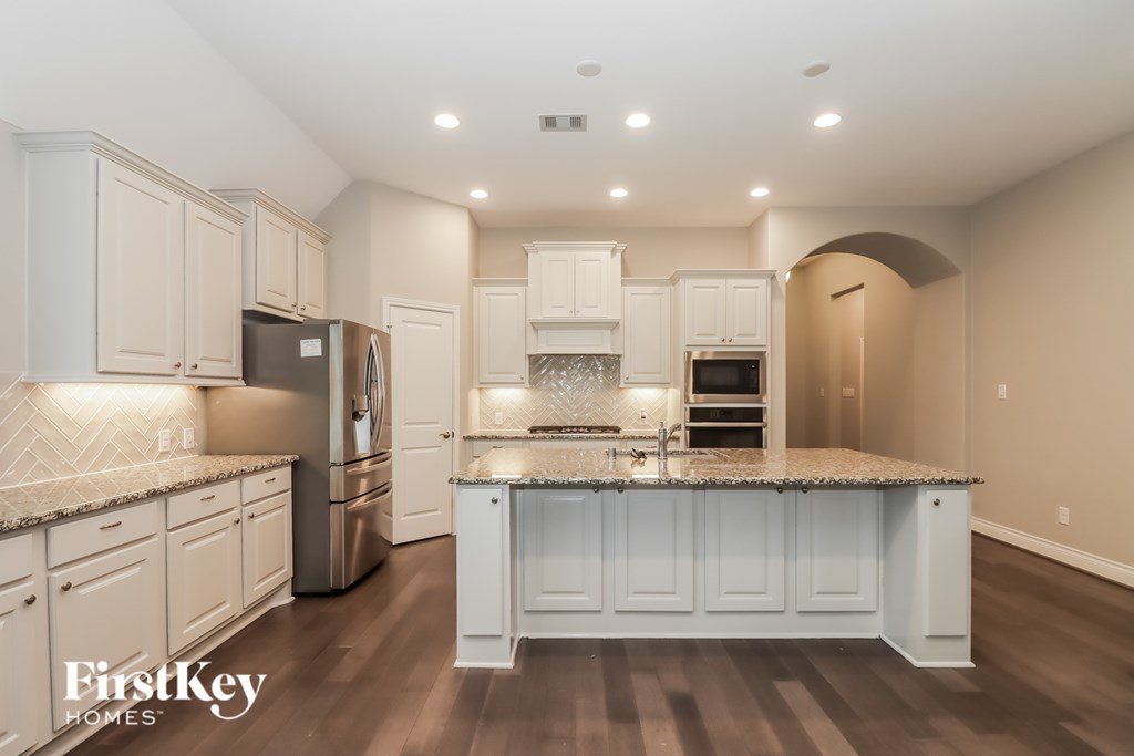A kitchen with a refrigerator, oven, and sink.