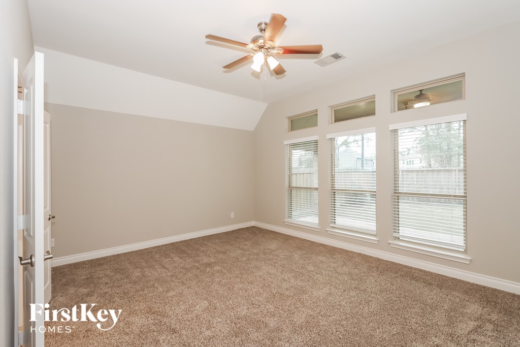 A room with a ceiling fan and carpeted floor.